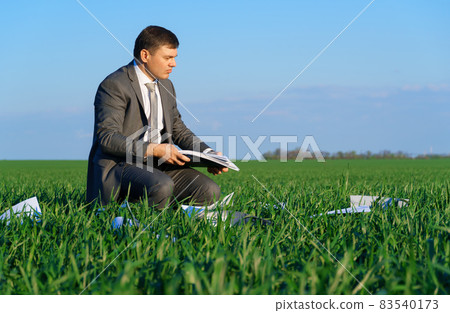 businessman works in a green field, freelance and business concept, green grass and blue sky as background 83540173