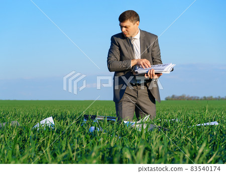 businessman works in a green field, freelance and business concept, green grass and blue sky as background businessman works in a green field, freelance and business concept, green grass and blue sky as background 83540174