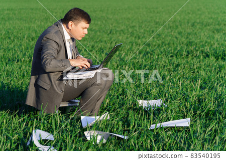 businessman works in a green field, freelance and business concept, green grass and blue sky as background 83540195