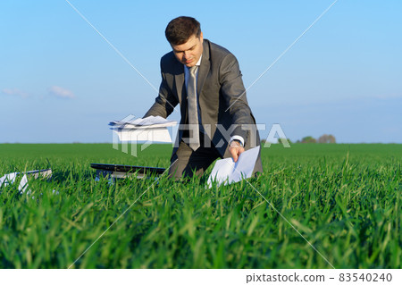 businessman works in a green field, freelance and business concept, green grass and blue sky as background 83540240