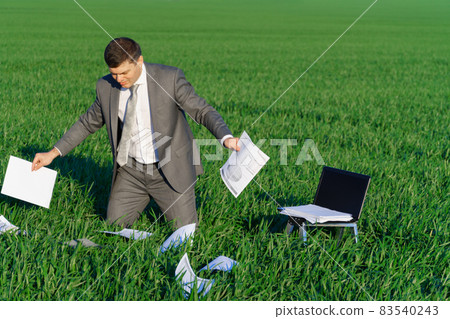 businessman works in a green field, freelance and business concept, green grass and blue sky as background 83540243