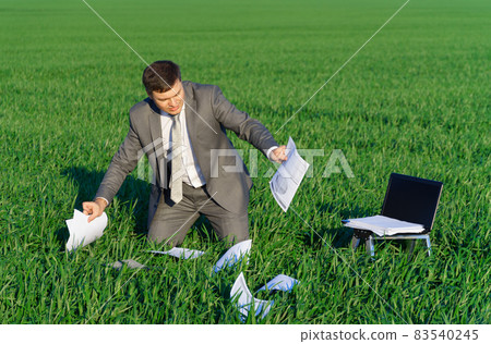 businessman works in a green field, freelance and business concept, green grass and blue sky as background businessman works in a green field, freelance and business concept, green grass and blue sky as background 83540245