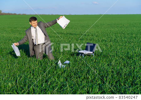 businessman works in a green field, freelance and business concept, green grass and blue sky as background businessman works in a green field, freelance and business concept, green grass and blue sky as background 83540247
