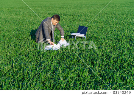 businessman works in a green field, freelance and business concept, green grass and blue sky as background businessman works in a green field, freelance and business concept, green grass and blue sky as background 83540249