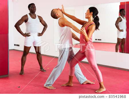 Woman exercising with man during self-defence training 83541968
