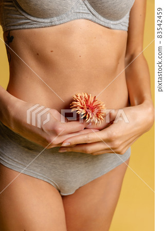 Beautiful body of young slim woman in gray underwear isolated on yellow studio background. Natural beauty concept. 83542459