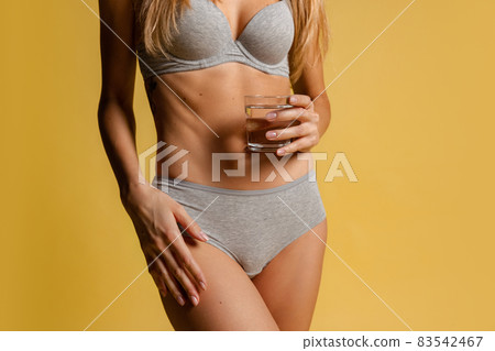 Beautiful body of young slim woman in gray underwear isolated on yellow studio background. Natural beauty concept. Beautiful body of young slim woman in gray underwear isolated on yellow studio background. Natural beauty concept. 83542467
