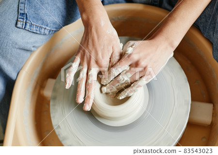 Woman Shaping Pottery on Wheel Close Up 83543023