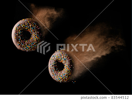 chocolate round donuts with multicolored sugar sprinkles levitate in a cloud of brown cocoa on a black background 83544512