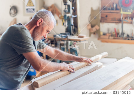 Standing senior man sanding wood with his arms Standing senior man sanding wood with his arms 83545015