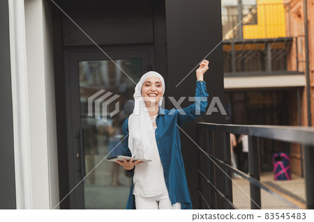 Modern Arabian muslim woman with tablet computer outdoors 83545483