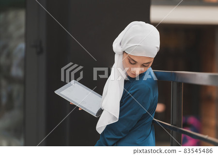 Beautiful muslim girl using digital tablet for communication with friend outdoor Beautiful muslim girl using digital tablet for communication with friend outdoor 83545486