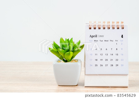April 2022 desk calendar on wooden table. 83545629