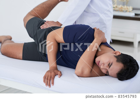 Horizontal shot of young Asian man getting physical rehabilitation manipulations at professional physical therapists 83545793