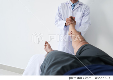 Horizontal shot of unrecognizable osteopathic physician working with male patient holding his leg doing foot joint manipulation Horizontal shot of unrecognizable osteopathic physician working with male patient holding his leg doing foot joint manipulation 83545803
