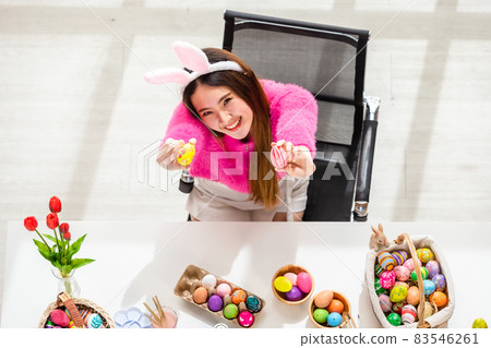 Easter holiday concept,Happy Asian Young woman holding with colorful Easter eggs on white wooden table background in top view 83546261