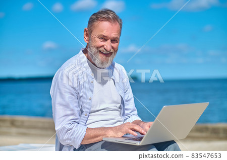 Smiling mature man with laptop in nature Smiling mature man with laptop in nature 83547653