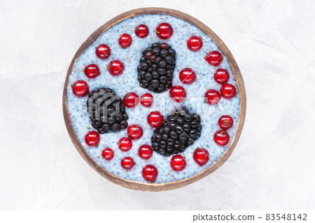 Overnight blue spirulina or blue matcha chia seed pudding with fresh blackberries and red currant berries in a trendy coconut bowl. Copy space, selective focus. Superfood and vegan food concept Overnight blue spirulina or blue matcha chia seed pudding with fresh blackberries and red currant berries in a trendy coconut bowl. Copy space, selective focus. Superfood and vegan food concept 83548142