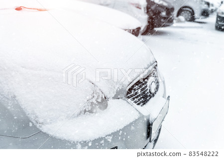 Cars parked in row at outdoor parking in winter. Vehicles covered by snow during heavy snowfall. Snowstorm or blizzard cold season weather forecast. Ice storm automobile park lot storage at morning Cars parked in row at outdoor parking in winter. Vehicles covered by snow during heavy snowfall. Snowstorm or blizzard cold season weather forecast. Ice storm automobile park lot storage at morning 83548222