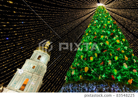Beautiful scenic decorated Christmas Tree with decorations and illuminated by light garlands against Sophia Cathedral on background Sofievska square market. Happy 2022 New Year and xmas Celebration Beautiful scenic decorated Christmas Tree with decorations and illuminated by light garlands against Sophia Cathedral on background Sofievska square market. Happy 2022 New Year and xmas Celebration 83548225