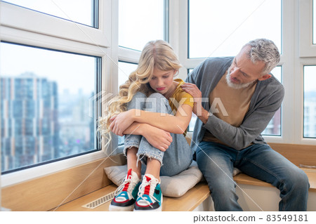 A teenage girl feeling upset and her father supporting her A teenage girl feeling upset and her father supporting her 83549181