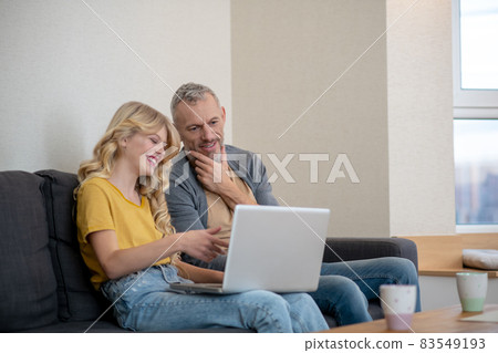 Father and daughter watching something on a laptop Father and daughter watching something on a laptop 83549193