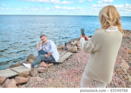 Woman with back to camera photographing man 83549766