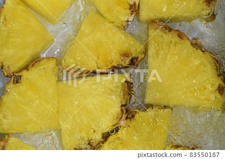 Slices of pineapple in water on white background. Pineapple close-up in liquid with bubbles. Slices of ripe pineapple in water. Macro image of fruits in water 83550187