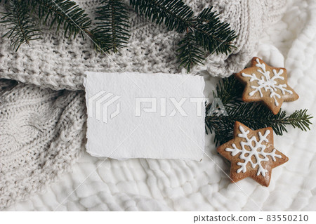 Christmas composition. Blank cotton card mockup, star shaped gingerbread cookies and fir tree branches. White muslin cotton table cloth, throw. Flatlay, top view. Winter holiday lifestyle concept. Christmas composition. Blank cotton card mockup, star shaped gingerbread cookies and fir tree branches. White muslin cotton table cloth, throw. Flatlay, top view. Winter holiday lifestyle concept. 83550210