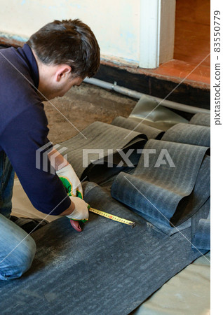 The master prepares a bituminous tape for installation, protection of a floor against moisture. 83550779