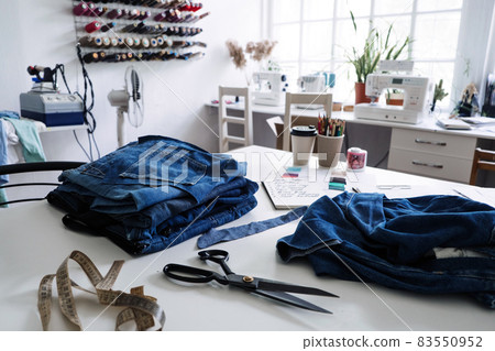 Denim Upcycling Ideas, Using Old Jeans, Repurposing Jeans, Reusing Old Jeans, Upcycle Stuff. Stack of old blue jeans, scissors, thread and sewing tools in sewing studio. Selective focus Denim Upcycling Ideas, Using Old Jeans, Repurposing Jeans, Reusing Old Jeans, Upcycle Stuff. Stack of old blue jeans, scissors, thread and sewing tools in sewing studio. Selective focus 83550952