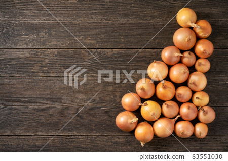 yellow onions on a wooden table, top view. 83551030