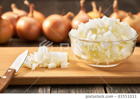 chopped onions in a glass bowl on a wooden table. chopped onions in a glass bowl on a wooden table. 83551031
