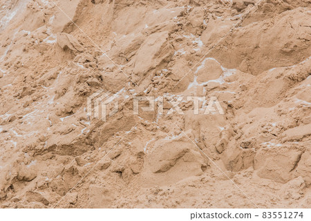 A large pile of sand of natural industrial material is stored outdoors on the territory of the plant 83551274
