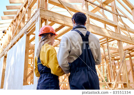 rear view on architects constructors holding clipboard blueprints at construction site rear view on architects constructors holding clipboard blueprints at construction site 83551334