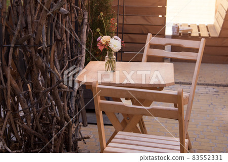 Empty chairs in outdoor cafe or restaurant. Wooden tables and chairs at sidewalk cafe Empty chairs in outdoor cafe or restaurant. Wooden tables and chairs at sidewalk cafe 83552331