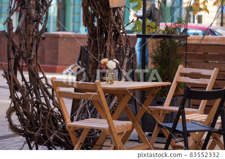 Empty chairs in outdoor cafe or restaurant. Wooden tables and chairs at sidewalk cafe Empty chairs in outdoor cafe or restaurant. Wooden tables and chairs at sidewalk cafe 83552332