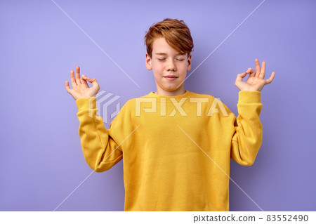 Cute teenage boy keep calm, meditating, isolated on purple studio background 83552490
