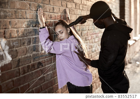 Black Thief armed man rob woman by gun on street, female is so scared, shocked face 83552517