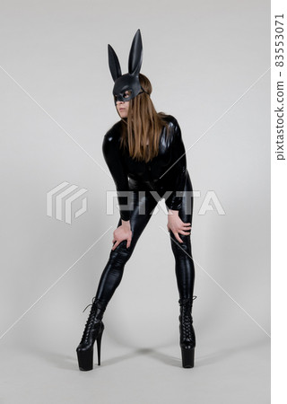 Sexy beautiful woman pole dancer posing in latex costume on background. Easter bunny concept. 83553071