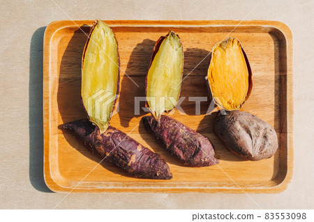 Sweet potato cut into half on wooden plate. 83553098