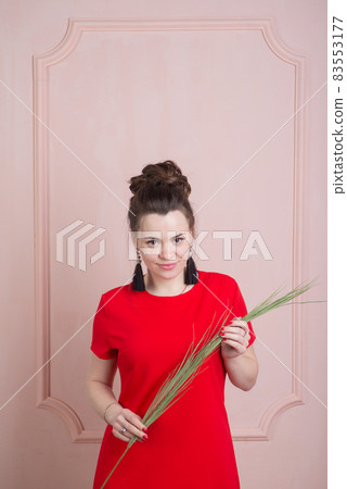 Beautiful woman in red dress posing against the wall in rococo style 83553177