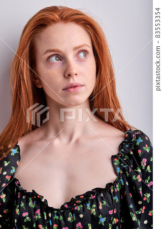Dreamy redhead female with long hair looking up thinking, isolated on white Dreamy redhead female with long hair looking up thinking, isolated on white 83553354