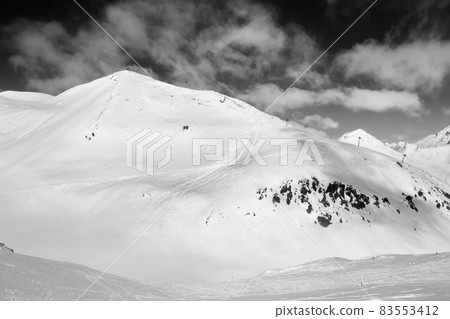 Snowy freeride trace and mountains with clouds. Black and white toned landscape. Snowy freeride trace and mountains with clouds. Black and white toned landscape. 83553412