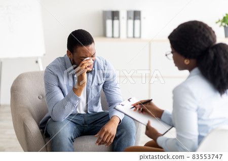 Depressed black guy crying at psychotherapist's office, seeking professional help at clinic Depressed black guy crying at psychotherapist's office, seeking professional help at clinic 83553747
