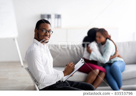 Male psychologist smiling while black lesbian couple hugging at office, reconciling and solving relationship problem 83553796
