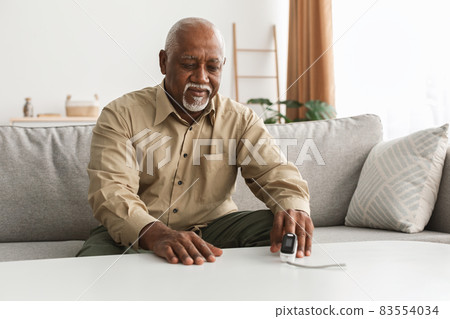 Senior Black Man Measuring Oxygen Saturation Using Pulse Oximeter Indoor Senior Black Man Measuring Oxygen Saturation Using Pulse Oximeter Indoor 83554034