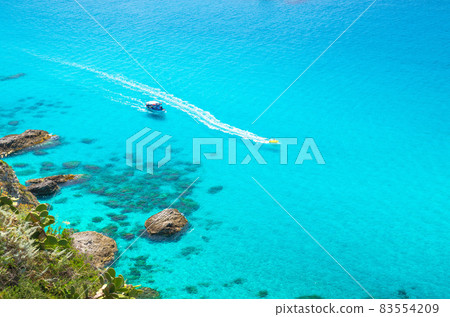 Fishing yacht and rubber boat in Capo Vaticano lagoon, Calabria, Italy 83554209