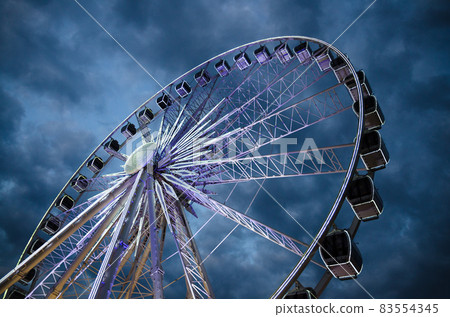 Big luminous ferris wheel in front of dark blue dramatic sky 83554345