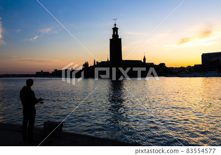 Silhouette of fisherman with pole and Stockholm City Hall, Sweden Silhouette of fisherman with pole and Stockholm City Hall, Sweden 83554577
